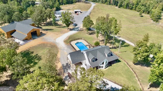 an aerial view of a house with swimming pool and large trees