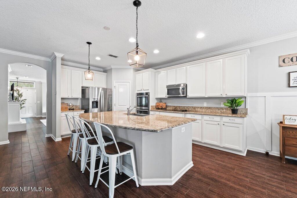 81015 Lockhaven Drive Yulee, FL 32097 - Photo 17 of 55 a kitchen with stainless steel appliances kitchen island granite countertop a wooden floor and white cabinets