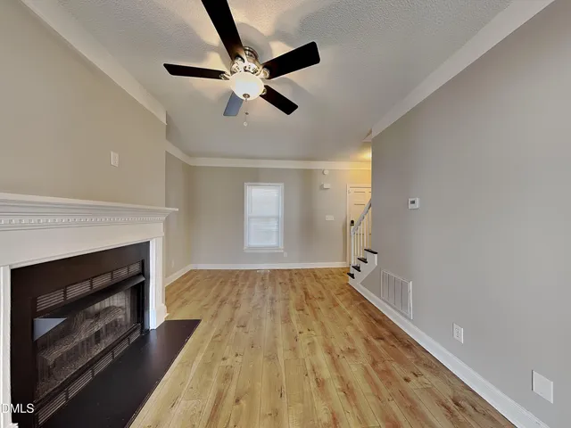 a view of an empty room and chandelier fan