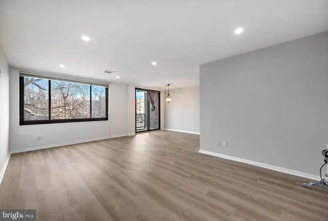 a view of an empty room with wooden floor and a window