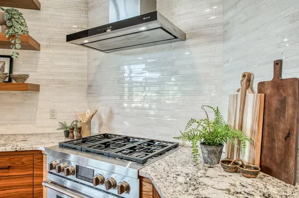 a large kitchen with stainless steel appliances a large counter top a stove and a wooden floors