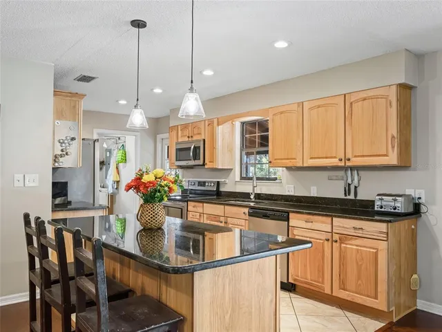 a kitchen with stainless steel appliances granite countertop a sink a stove a microwave a dining table chairs and cabinets