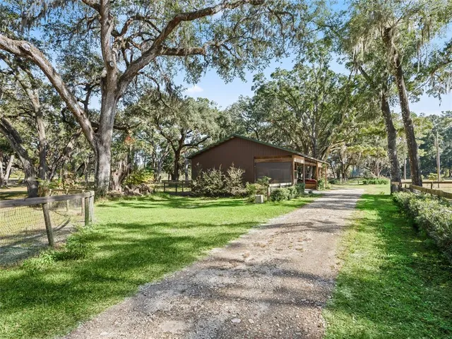 a view of a house with a big yard and large trees