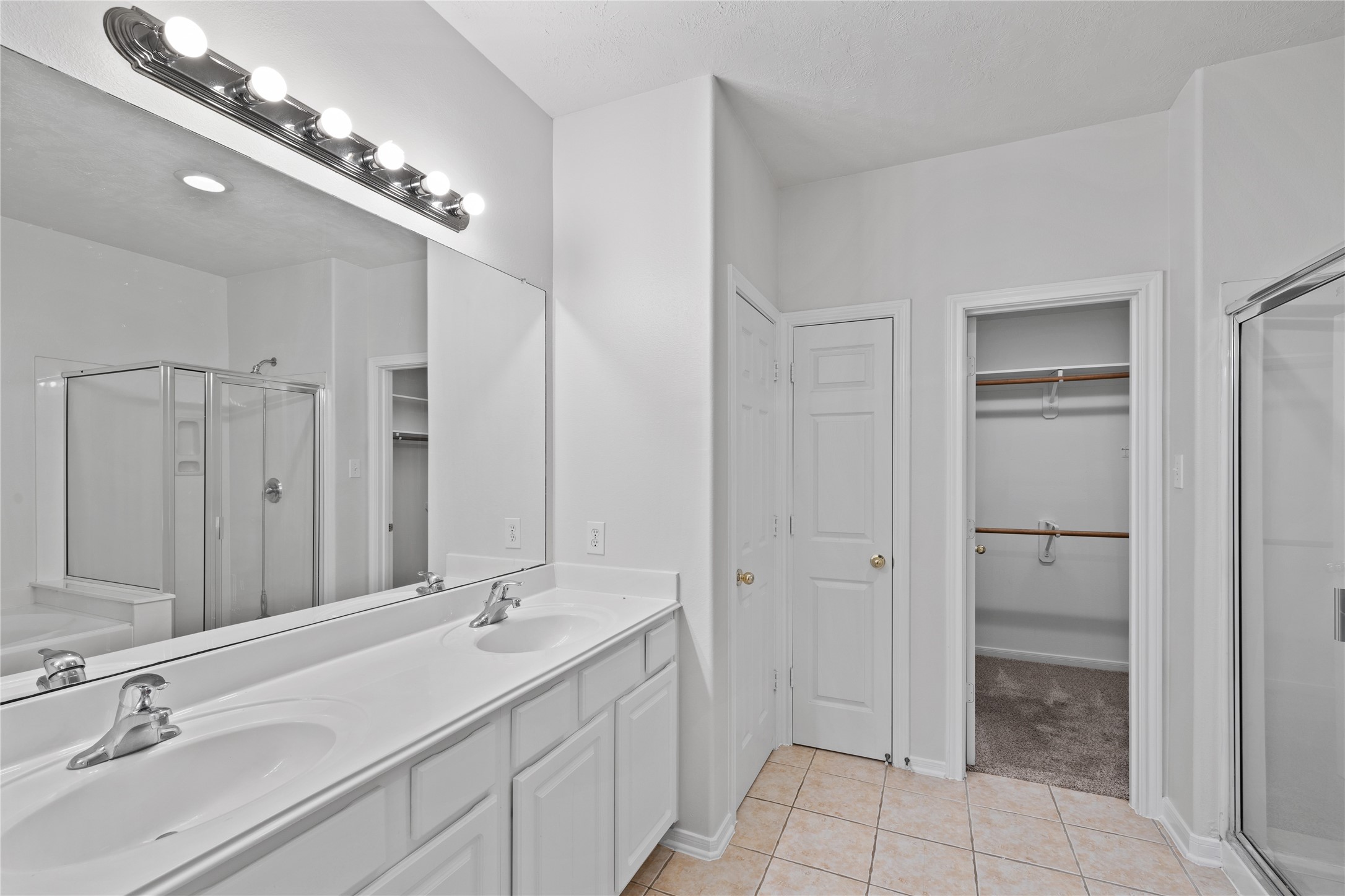 107 West Burberry Circle The Woodlands, TX 77384 - Photo 18 of 28 a bathroom with a double vanity sink a large mirror and a shower