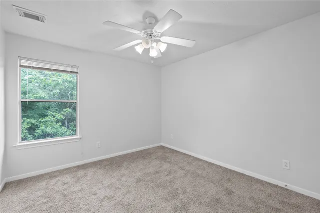 an empty room with a chandelier fan and windows