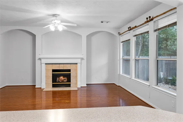 a view of an empty room with wooden floor fireplace and a window