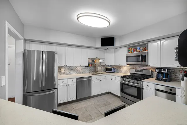 a kitchen with stainless steel appliances granite countertop a stove top oven a sink and a refrigerator