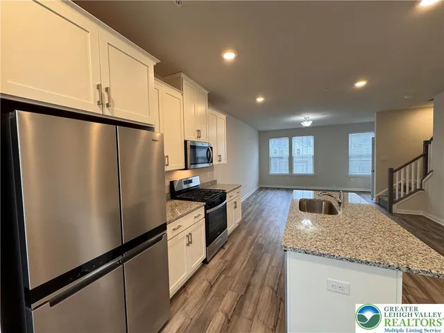 a kitchen with granite countertop a refrigerator a sink and wooden cabinets
