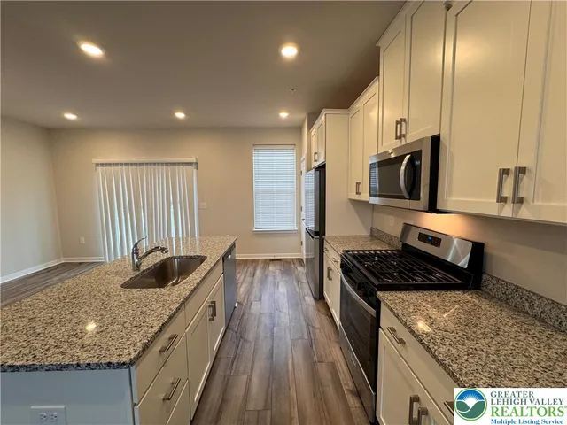 a kitchen with granite countertop stainless steel appliances sink stove microwave and cabinets