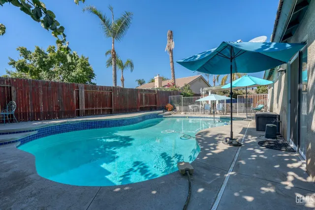 a view of a backyard with table and chairs under an umbrella with a small yard