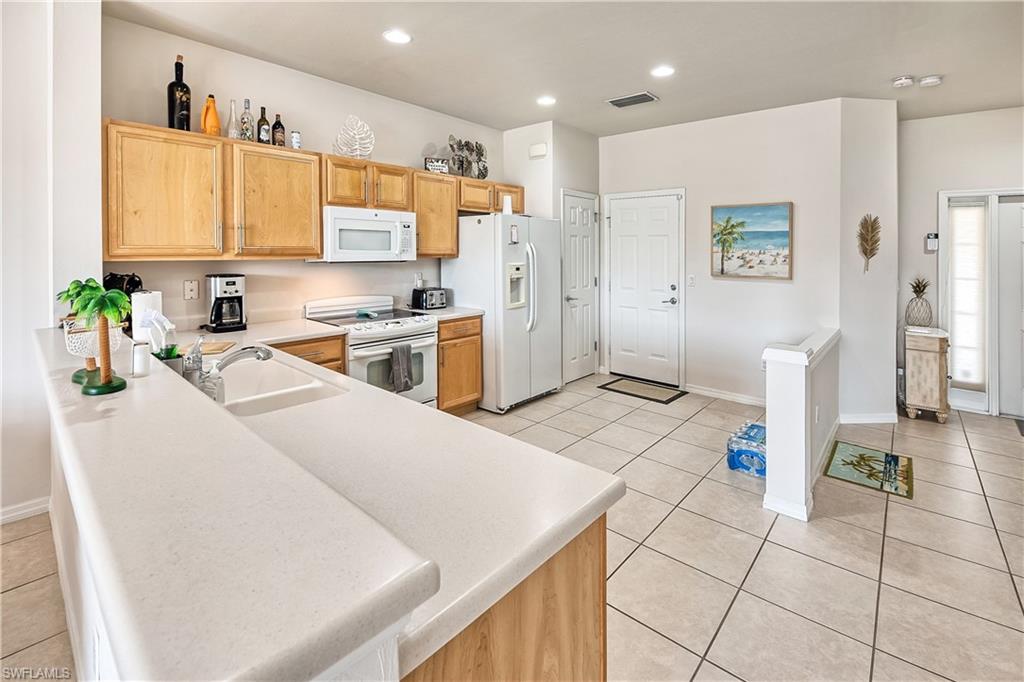 16211 Ravina Way, Unit 18 Naples, FL 34110 - Photo 9 of 24 a kitchen with a sink a stove a refrigerator a stove top oven a dining table and chairs