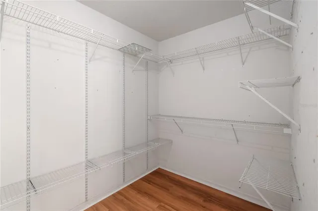 an empty room with wooden floor closet and windows
