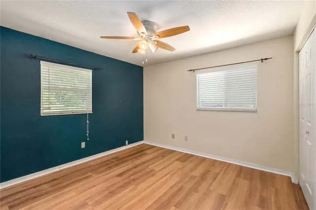 wooden floor in an empty room with a chandelier fan