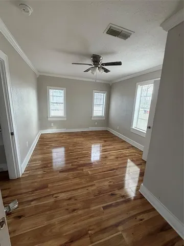 a view of empty room with wooden floor and fan