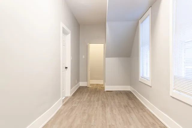 a view of hallway with window and wooden floor