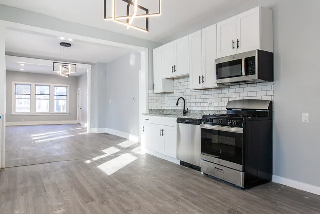 a kitchen with stainless steel appliances granite countertop a stove a sink and a microwave