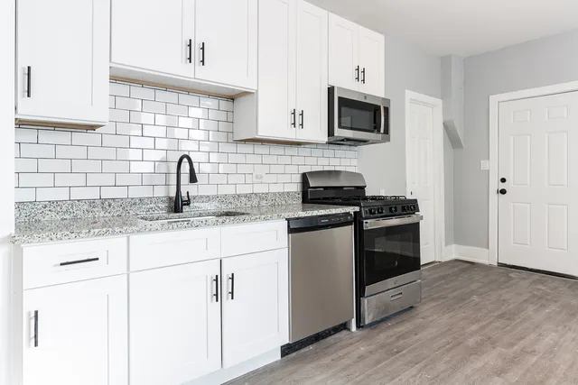 a kitchen with granite countertop white cabinets and stainless steel appliances