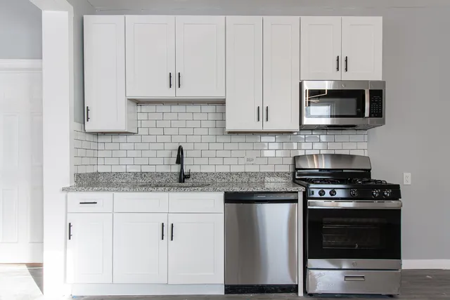 a kitchen with granite countertop white cabinets and stainless steel appliances