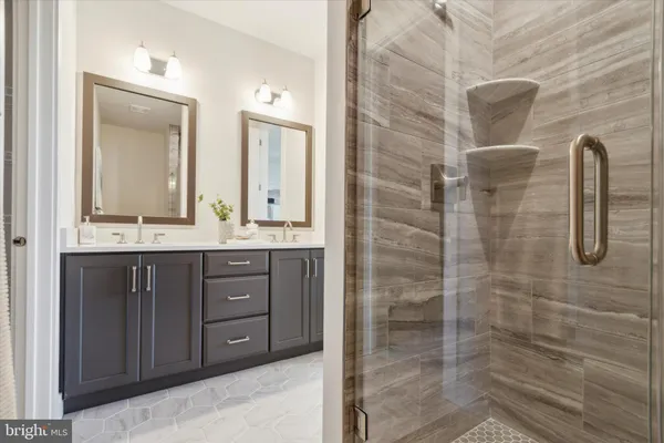 a bathroom with a double vanity sink a toilet a mirror and shower