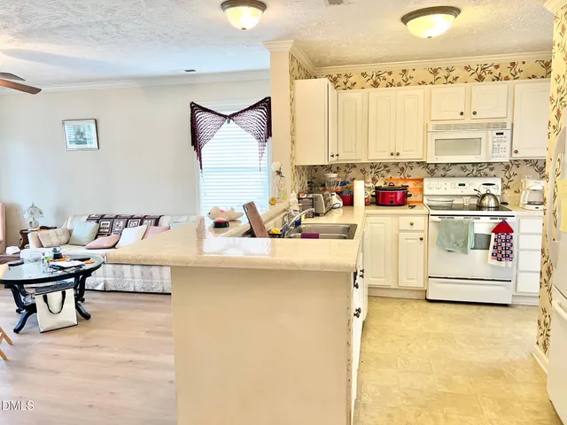 a kitchen with kitchen island a stove a sink and white cabinets with wooden floor
