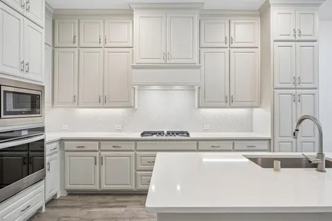 a kitchen with white cabinets and sink