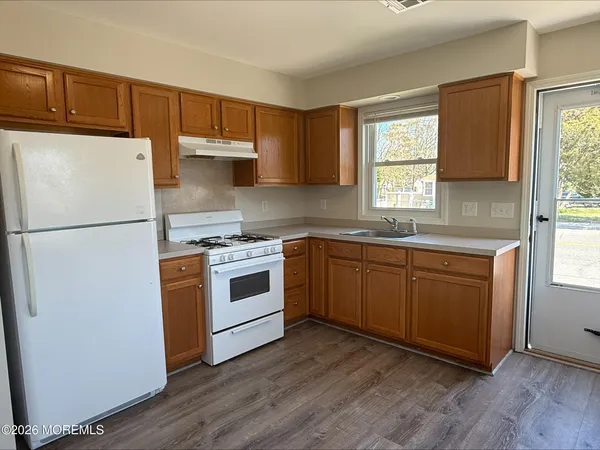 a kitchen with a white cabinets a sink a window a wooden floor and stainless steel appliances