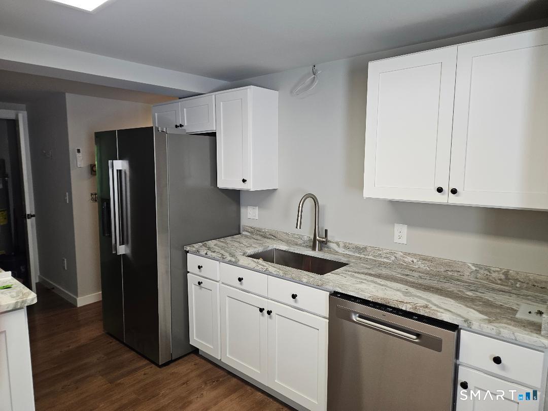 300 Railtree Hill Road Woodbury, CT 06798 - Photo 3 of 7 a kitchen with stainless steel appliances granite countertop a refrigerator sink and white cabinets with wooden floor