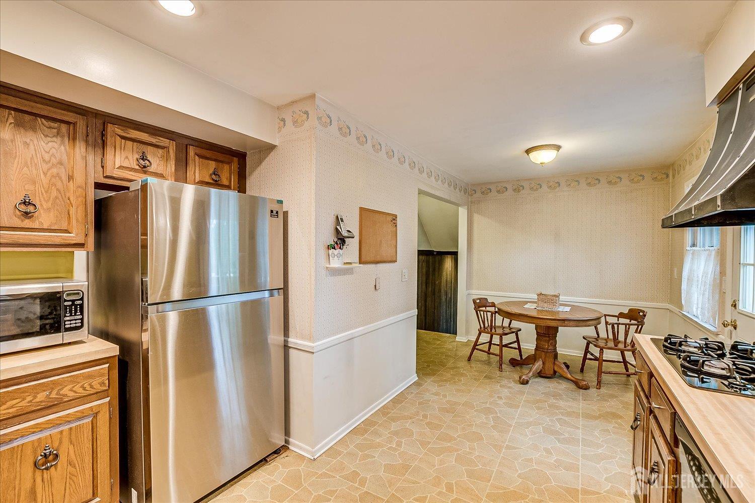 4 Bodnarik Road Edison, NJ 08837 - Photo 17 of 41 a kitchen with stainless steel appliances a refrigerator a stove a dining table and chairs with wooden floor