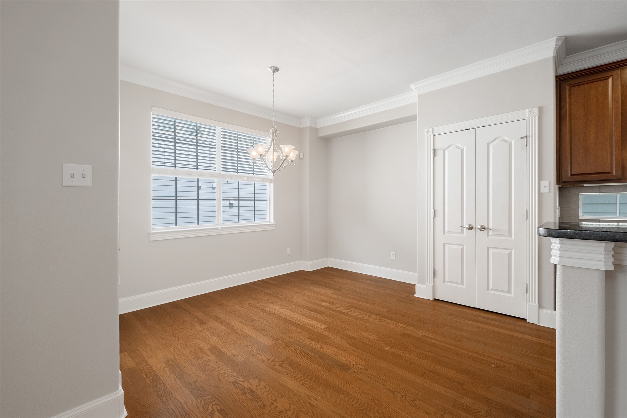 6715 Windrift Way, Unit 8 Austin, TX 78745 - Photo 9 of 24 Hardwood flooring extends throughout this well-lit dining area, featuring a decorative chandelier and bright window.