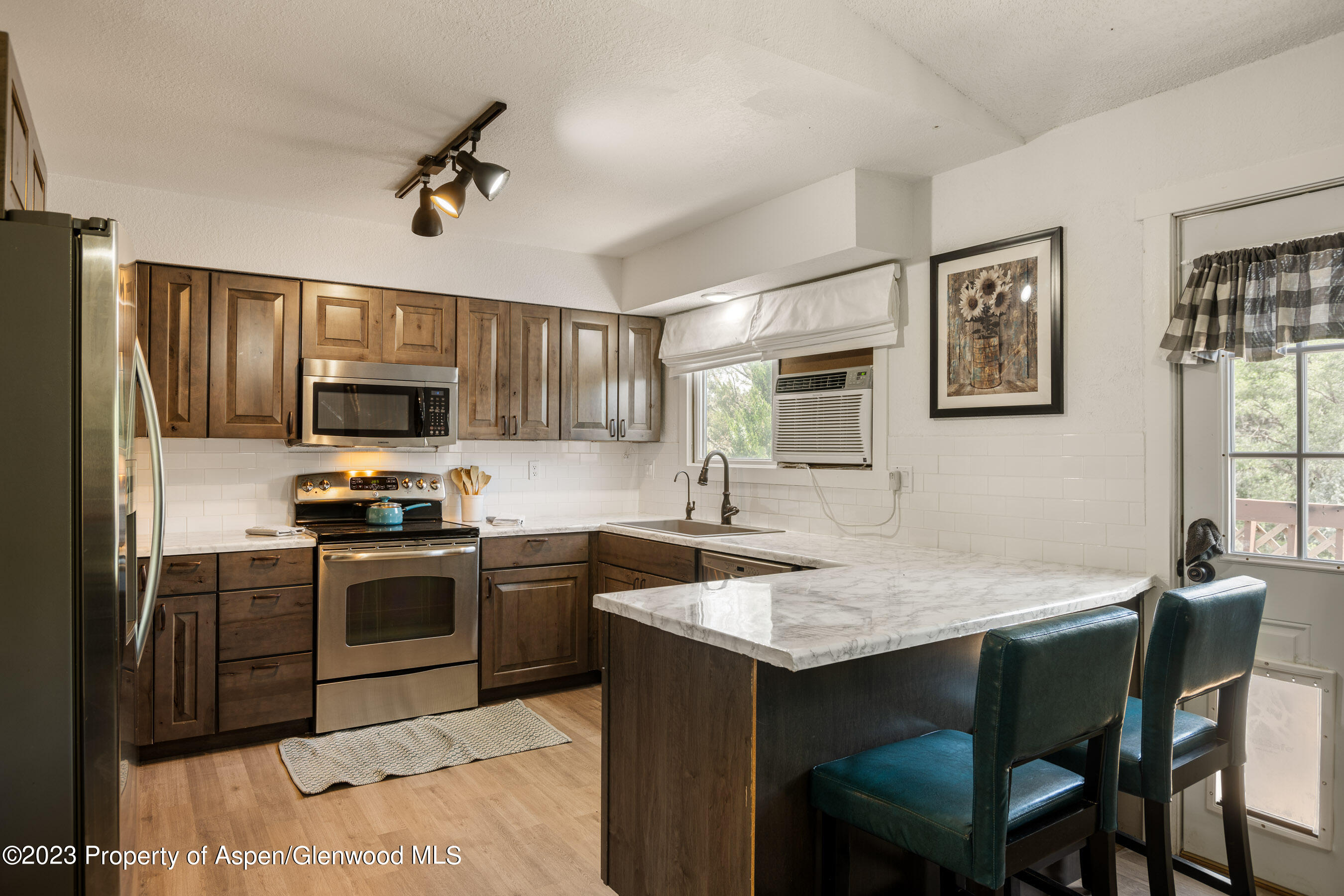 1332 Arabian Avenue Rifle, CO 81650 - Photo 3 of 23 a kitchen with stainless steel appliances granite countertop a kitchen island hardwood floor sink stove dining table and chairs