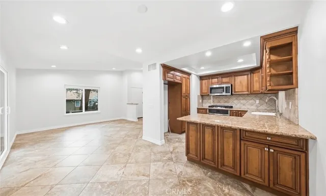 a kitchen with stainless steel appliances granite countertop a stove a sink and a refrigerator