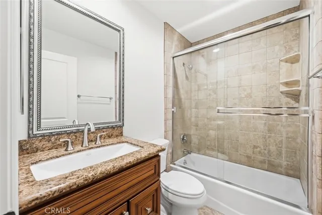 a bathroom with a granite countertop sink a toilet and shower