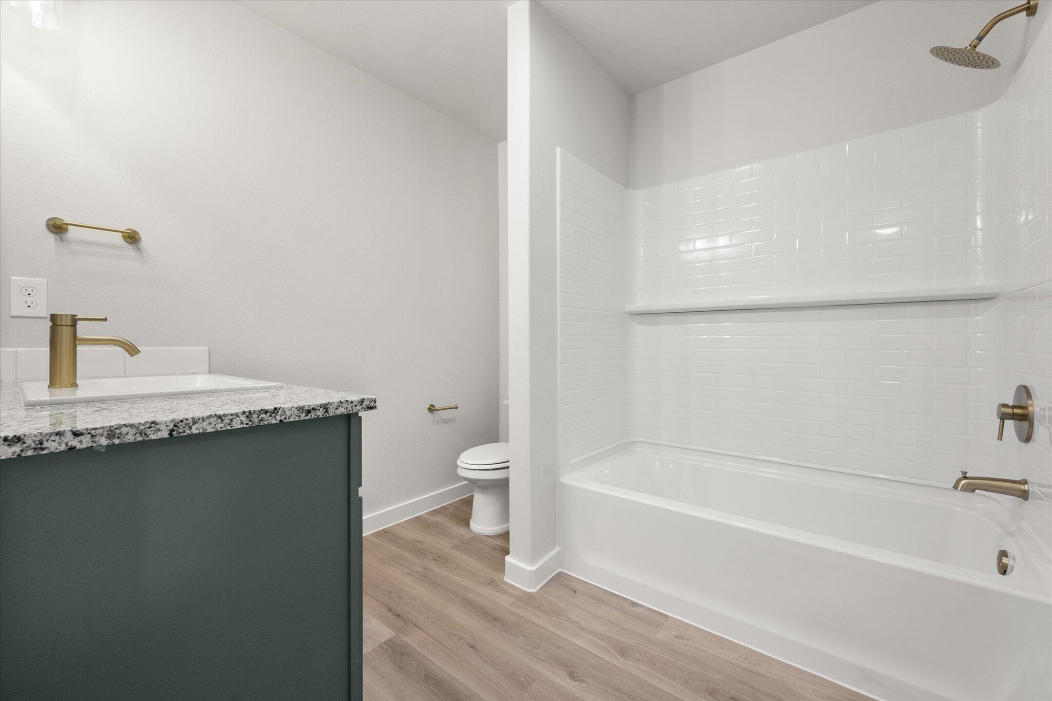 8605 29th Street Lubbock, TX 79407 - Photo 15 of 21 a bathroom with a granite countertop sink a toilet and bathtub