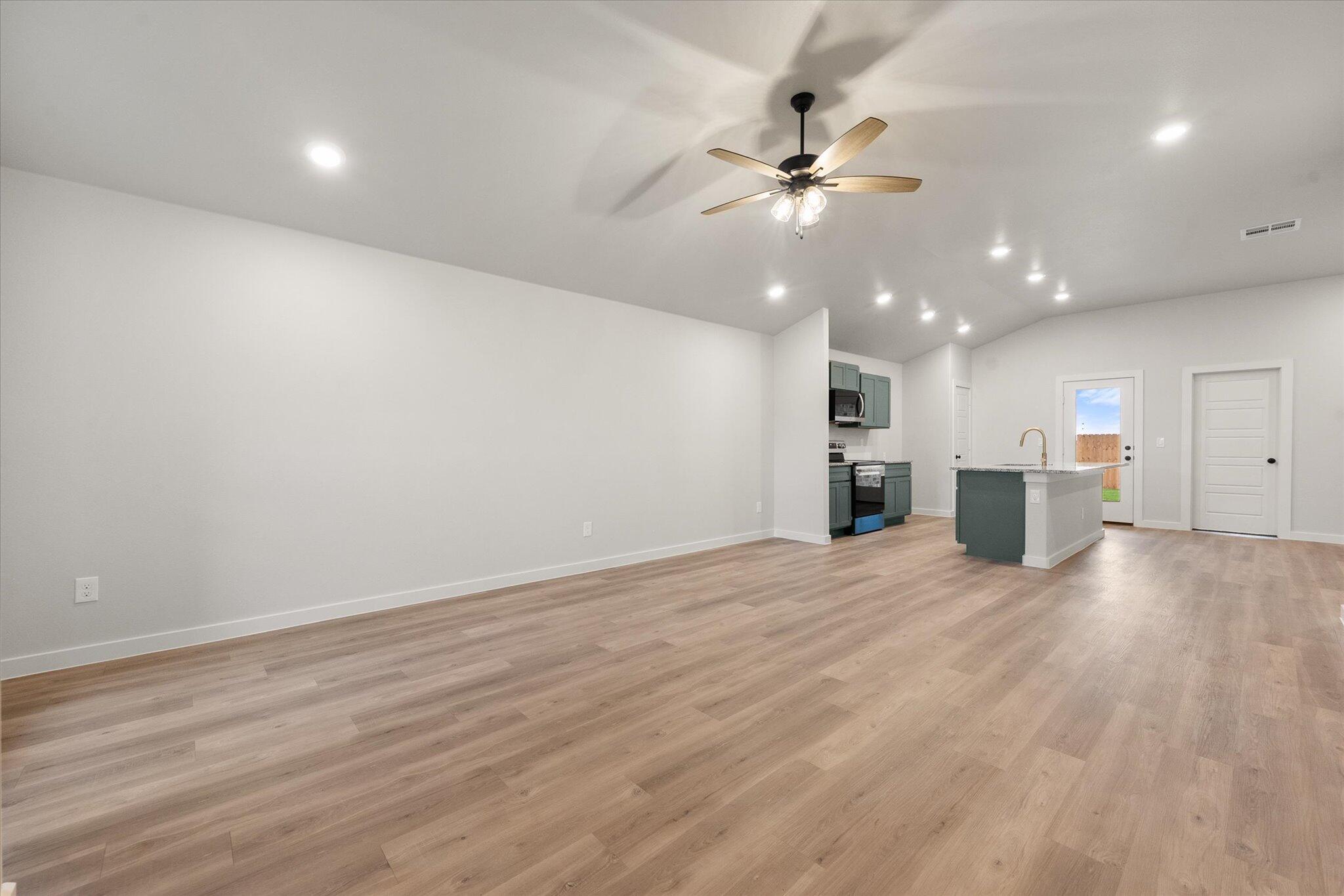 8605 29th Street Lubbock, TX 79407 - Photo 3 of 21 an empty room with wooden floor ceiling fan and kitchen view