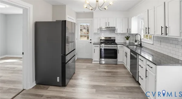 a kitchen with stainless steel appliances granite countertop a refrigerator a stove a sink and a granite counter tops with white cabinets