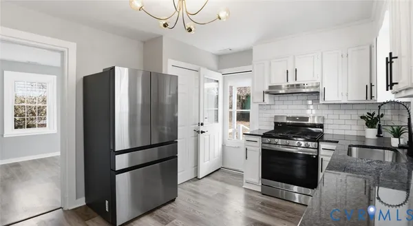 a kitchen with stainless steel appliances granite countertop a refrigerator stove and white cabinets
