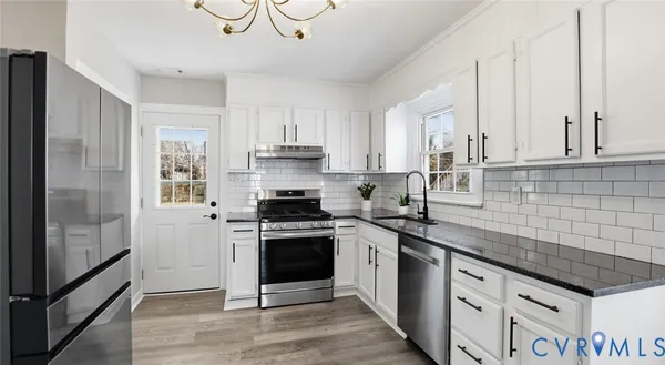 a kitchen with stainless steel appliances granite countertop a stove a sink and a refrigerator