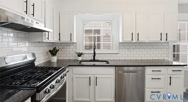 a kitchen with granite countertop a sink stove and cabinets