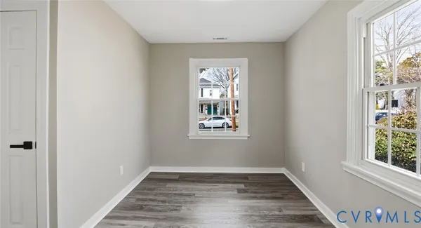 a view of an empty room with wooden floor and a window