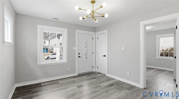 a view of an empty room with a window and wooden floor