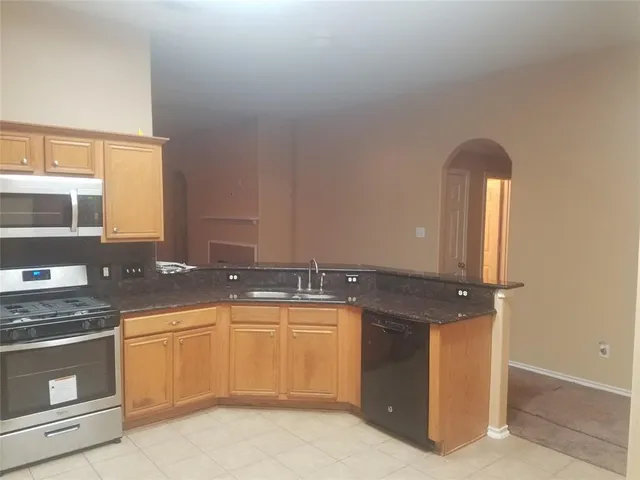 a kitchen with granite countertop a stove sink and microwave