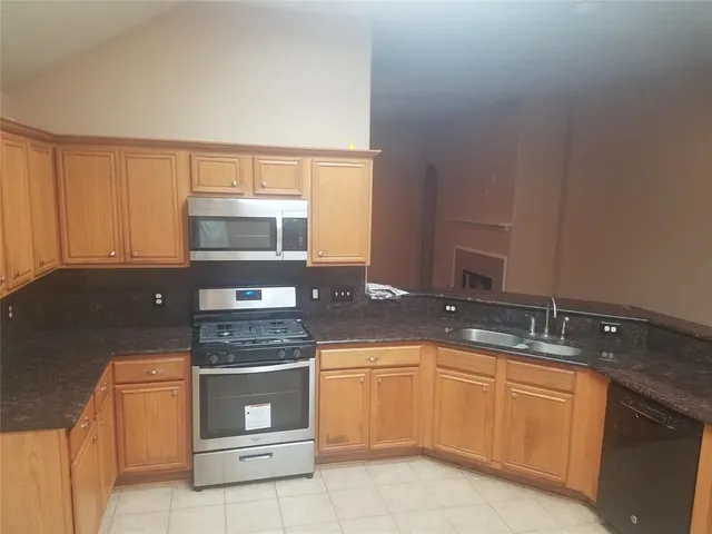 a kitchen with granite countertop a sink a stove and cabinets