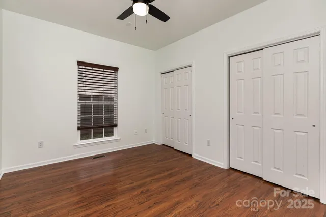 an empty room with wooden floor cabinet and windows