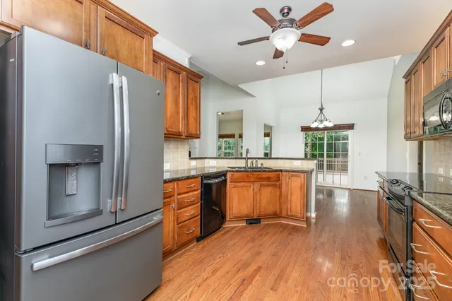 a kitchen with stainless steel appliances granite countertop a refrigerator a stove and a wooden floors