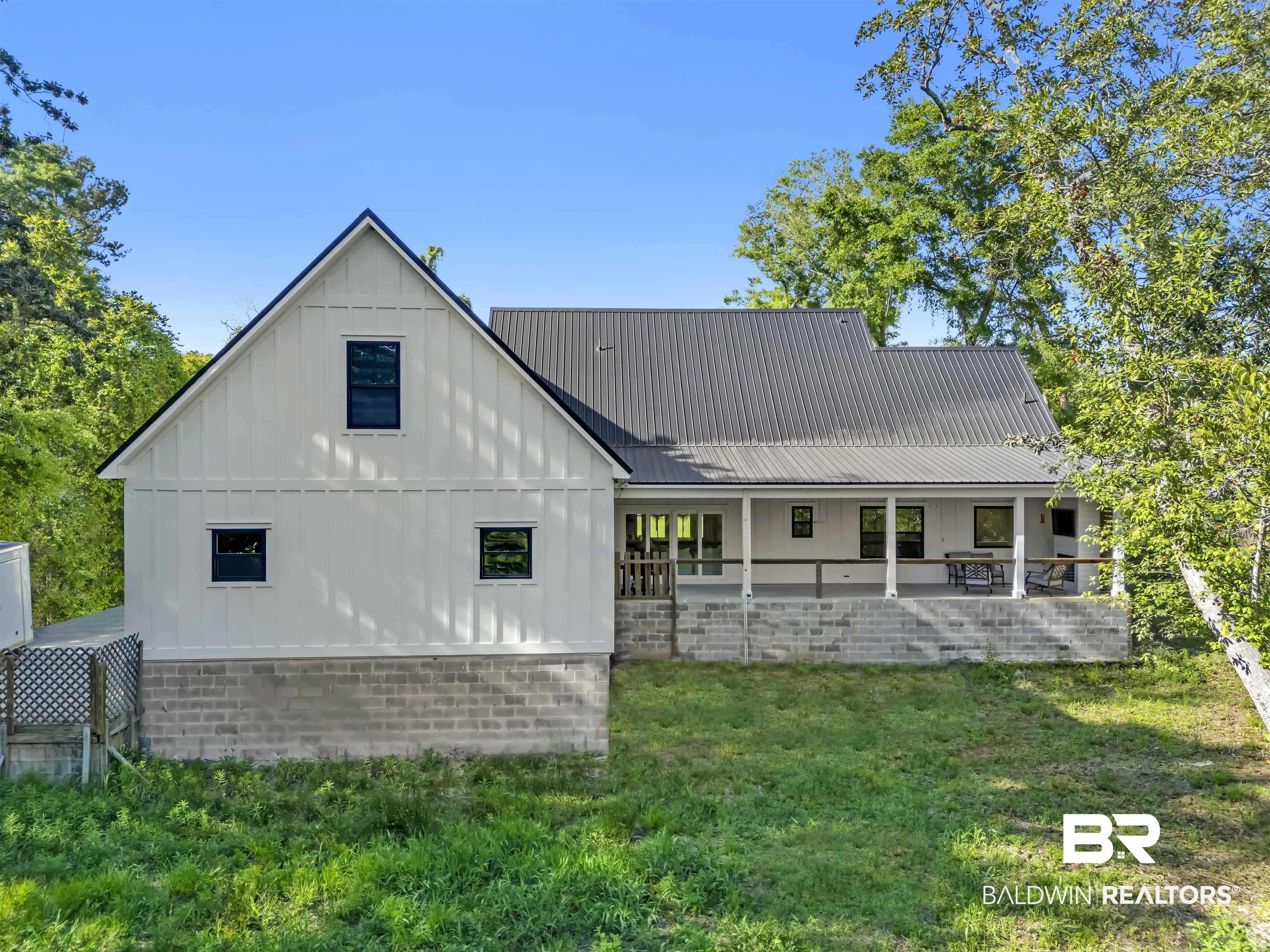 19058 James Road Gulf Shores, AL 36542 - Photo 41 of 49 Back of house with board and batten siding, a metal roof, and a yard