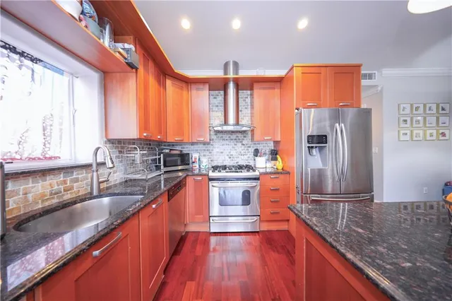 a kitchen with stainless steel appliances granite countertop a refrigerator a sink dishwasher a stove with wooden cabinets and floor