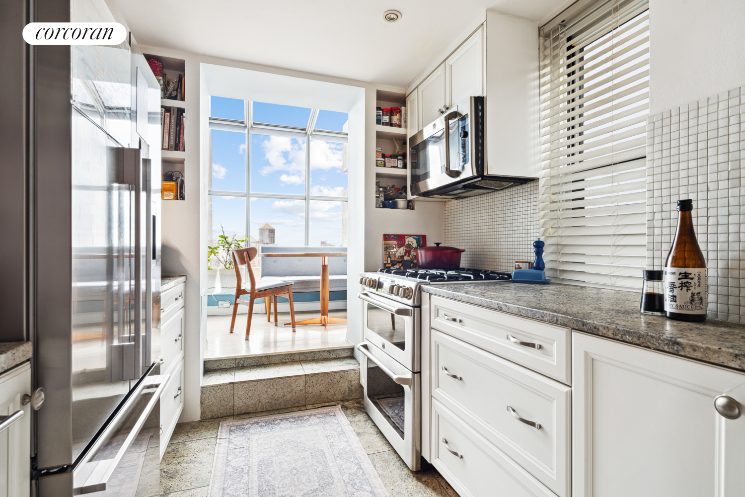 a kitchen with granite countertop a refrigerator and white cabinets