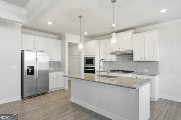 a kitchen with stainless steel appliances granite countertop a refrigerator a sink a stove and oven with wooden floor