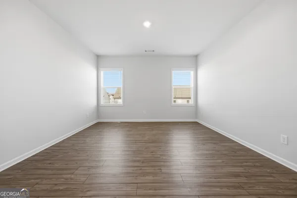 a view of an empty room with wooden floor and window