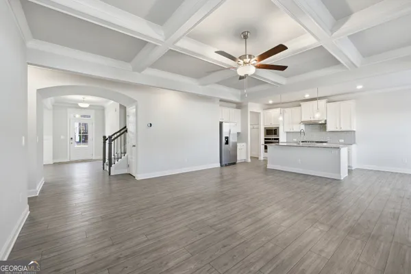 a view of a big room with wooden floor and a kitchen